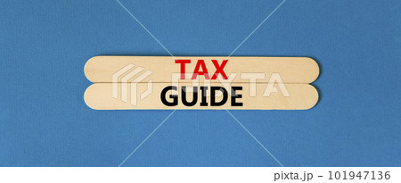 Tax guide symbol. Concept words Tax guide on beautiful wooden stick. Beautiful blue table blue background. Business and Tax guide concept. Copy space. 101947136