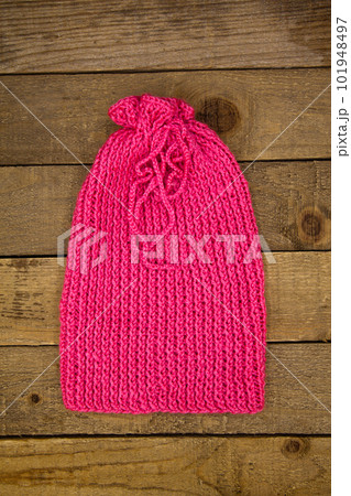 Handmade wool knitted winter pink hat and scarf on wood background Handmade wool knitted winter pink hat and scarf on wood background 101948497