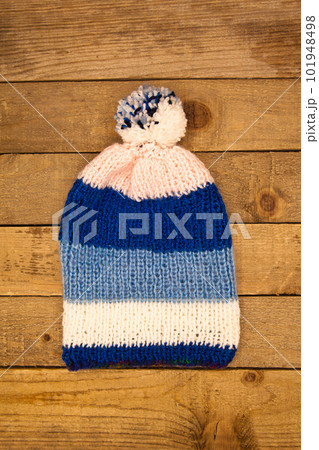 Handmade wool knitted winter blue and white hat and scarf on wood background Handmade wool knitted winter blue and white hat and scarf on wood background 101948498