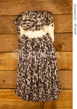 Handmade wool knitted winter grey and white hat and scarf on wood background 101948502