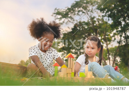 Happy cheerful ethnic girls play wooden block puzzle together at outdoors park , Relationship little kids, Diverse ethnic concept. 101948787