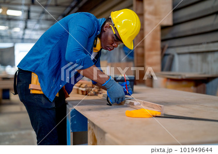 African American carpenter man use pencil to mark on timber for preparing wood product in workplace. African American carpenter man use pencil to mark on timber for preparing wood product in workplace. 101949644