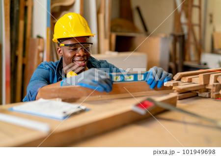 Professional American American carpenter man use level to check wood product in factory workplace Professional American American carpenter man use level to check wood product in factory workplace 101949698