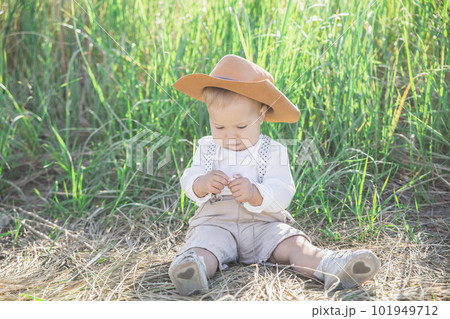 beautiful blond baby in a hat and suit with suspenders in the grass beautiful blond baby in a hat and suit with suspenders in the grass 101949712