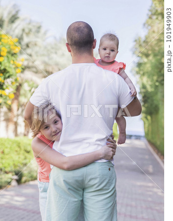 young father hugs his daughters in the garden young father hugs his daughters in the garden 101949903