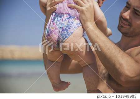 father holds newborn baby in a fish swimsuit on the beach father holds newborn baby in a fish swimsuit on the beach 101949905