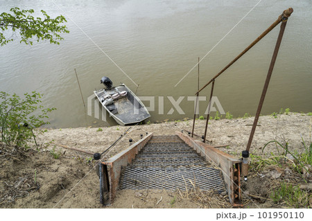 steep metal stairway leading down to water and a fishing boat on a shore of the Missouri River at Lupus, MO 101950110