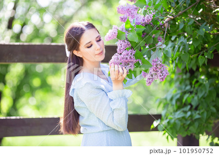 romantic girl in blue dress stands with lilac flowers, in the garden 101950752