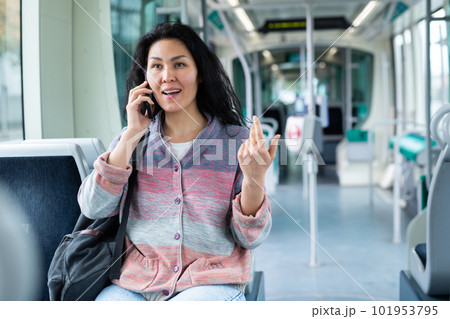 Oriental woman talking on mobile phone while riding a tram 101953795