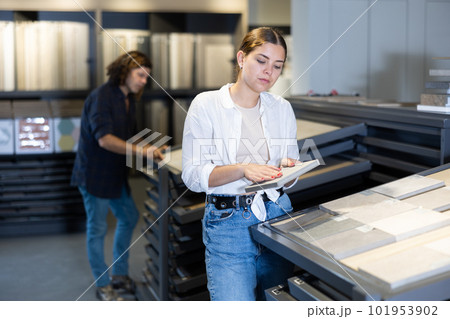 Girl customer choosing ceramic tile at building materials store 101953902