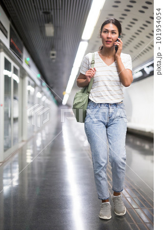 Oriental woman having telephone conversation in subway station 101954054