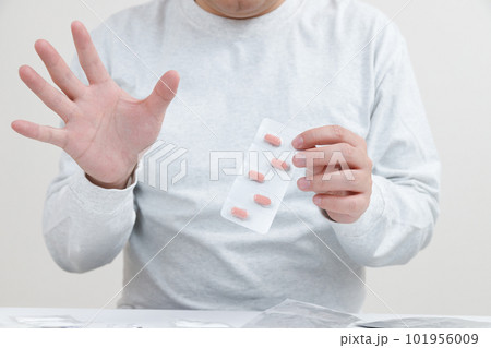 服薬拒否の男性。錠剤を手に持っている 101956009