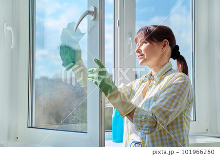 Woman cleaning windows at home using spray and microfiber cloth Woman cleaning windows at home using spray and microfiber cloth 101966280
