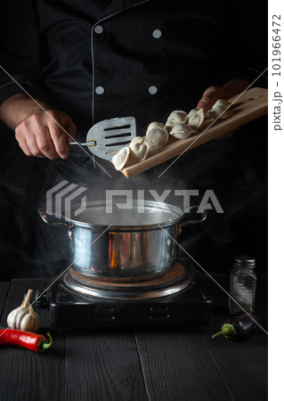 Professional chef cooks meat dumplings in a saucepan in the restaurant kitchen. Close-up of the hands of the cook during work. Free advertising space. Professional chef cooks meat dumplings in a saucepan in the restaurant kitchen. Close-up of the hands of the cook during work. Free advertising space. 101966472
