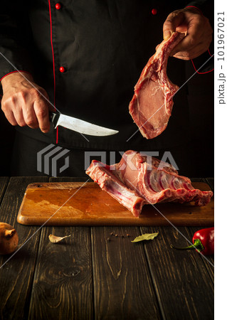 Cutting raw ribs with butcher hands on kitchen cutting board. Barbecue grill idea 101967021