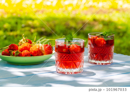 Strawberries in plate on the table and fresh drinks with mint on a sunny day Strawberries in plate on the table and fresh drinks with mint on a sunny day 101967033