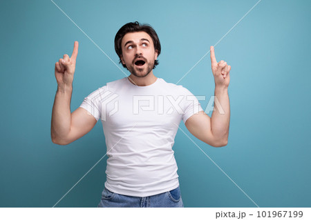 indignant stylish brutal brunette man in a white t-shirt points his finger to the side indignant stylish brutal brunette man in a white t-shirt points his finger to the side 101967199