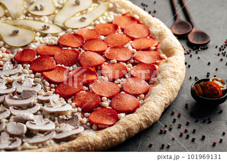 Big uncooked pizza with variety of toppings 101969131
