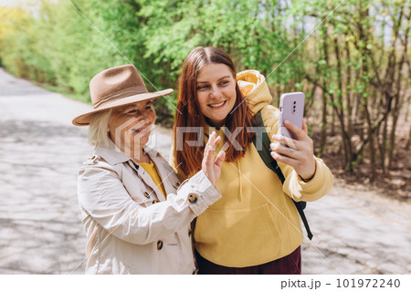 Two women together wear casual clothes doing selfie shot pov on mobile cell phone. Family day concept. Young woman and senior middle aged mom spending time together 101972240
