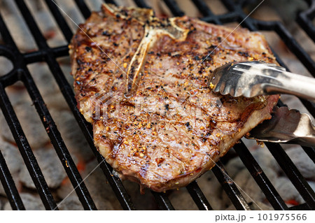 Beef steak being cooked on a grill 101975566