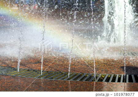 Close up of beautiful city fountain. Splashing upward crystal thin streams of clear cool transparent water, shiny droplets. Multicolored blurred rainbow, recreation area. Close up of beautiful city fountain. Splashing upward crystal thin streams of clear cool transparent water, shiny droplets. Multicolored blurred rainbow, recreation area. 101978077