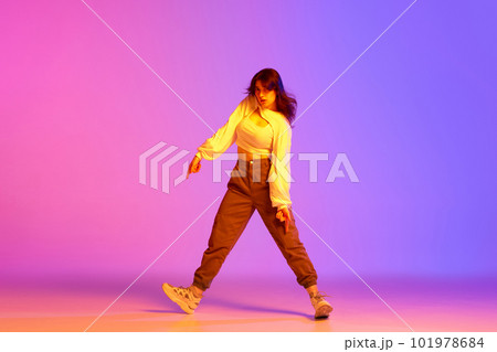 Young female dancer in sport style clothes making performance, training against gradient pink purple background in neon light Young female dancer in sport style clothes making performance, training against gradient pink purple background in neon light 101978684