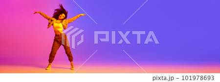 Young girl in sport style clothes dancing hip-hop against gradient pink purple background in neon light 101978693