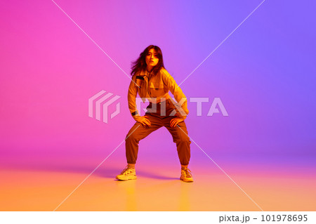 Active, artistic young woman, hip hop dancer in sport style clothes dancing against gradient pink purple background in neon light 101978695