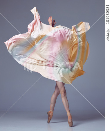 Young woman, ballerina dancing with elegance movements and fabric cover the face over grey studio background. Ballet with silk 101980381