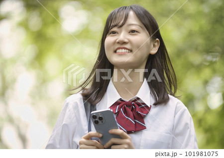新緑の中スマホを持つ女子高生 101981075