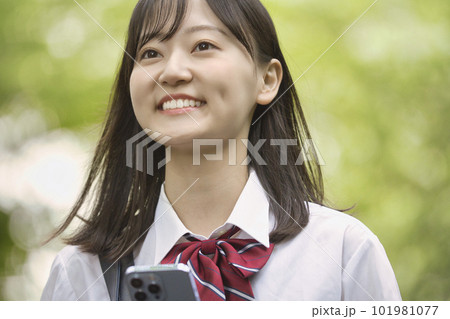 新緑の中スマホを持つ女子高生 新緑の中スマホを持つ女子高生 101981077
