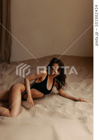 Attractive model posing in studio with sea sand. Attractive model posing in studio with sea sand. 101982434