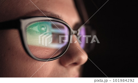 Attractive young businesswoman working at night via computer at office with, closeup of hipster student girl browsing the internet, looking at monitor of modern computer, focus on the glasses. 101984292