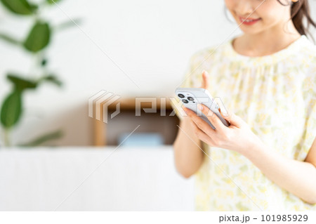 リビングでスマートフォンを操作する女性。 リビングでスマートフォンを操作する女性。 101985929