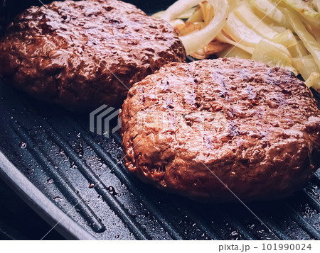 Cooking minced beef burger on cast iron grill skillet outdoors, red meat on frying pan, grilling food in the garden, English countryside living 101990024