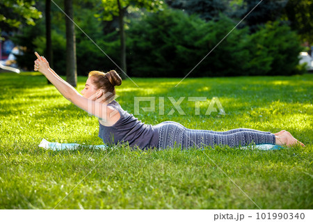 Young woman doing yoga exercises in the summer city park. 101990340