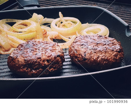 Cooking minced beef burger on cast iron grill skillet outdoors, red meat on frying pan, grilling food in the garden, English countryside living 101990936