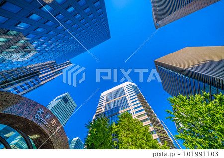 日本の東京都市景観　夏のような日差し。「大手町」交差点前の大手町駅や青空と新緑に映える摩天楼＝4月 101991103