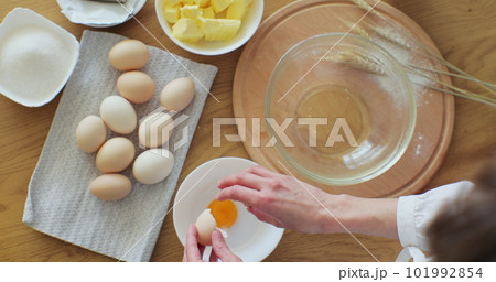 Woman cracking an egg into flour to make bread according to traditional recipe. Woman baking at home, enjoying hobby. 101992854