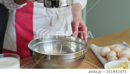 Closeup shot of woman sifting flour through sieve, starting to make bread with traditional methods. 101992871