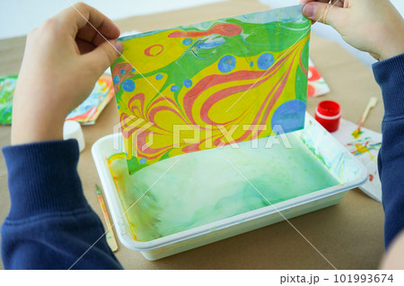 Boy is drawing Ebru and set of tools on table. Traditional Turkish Ebru technique. top view. Children development concept 101993674