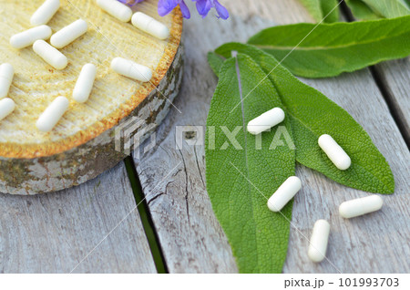 Leaves and flowers of medicinal sage lie on a wooden table next to homeopathic pills, herbal medicine, alternative medicine. Leaves and flowers of medicinal sage lie on a wooden table next to homeopathic pills, herbal medicine, alternative medicine. 101993703
