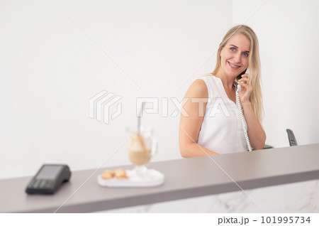 Receptionist in a beauty salon talking to a client on the phone.  101995734