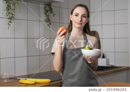 Portrait of a happy woman holding a plate of fresh salad and tossing a fresh apple up Portrait of a happy woman holding a plate of fresh salad and tossing a fresh apple up 101996265