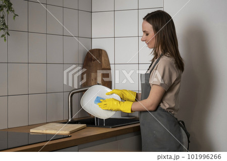 Woman washing dishes in kitchen, princess plate under tap water in sink Woman washing dishes in kitchen, princess plate under tap water in sink 101996266