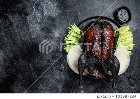 Traditional whole roasted Christmas Peking duck with herbs and sauce. Black background. Top view. Copy space Traditional whole roasted Christmas Peking duck with herbs and sauce. Black background. Top view. Copy space 101997834
