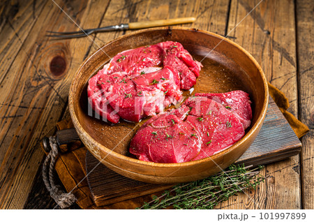 Fresh Mutton chop leg steaks, uncooked lamb meat with herbs. Wooden background. Top view 101997899