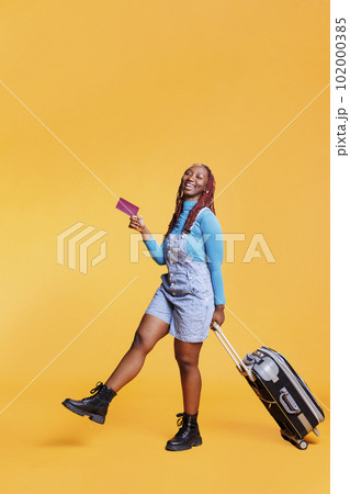 Smiling young traveller being excited about vacation trip abroad, leaving on international flight with passport. Cheerful female model enjoying weekend activities with baggage, holiday. Smiling young traveller being excited about vacation trip abroad, leaving on international flight with passport. Cheerful female model enjoying weekend activities with baggage, holiday. 102000385