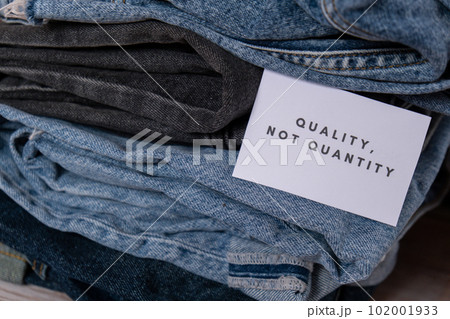 Quality not quantity text on paper note on Jeans clothes assortment Second hand sustainable shopping. Capsule minimal wardrobe. Sustainable fashion overconsumption, conscious buying consumption, slow 102001933
