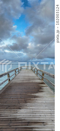 Empty wooden pier with dramatic sky and calm water Empty wooden pier with dramatic sky and calm water 102003124